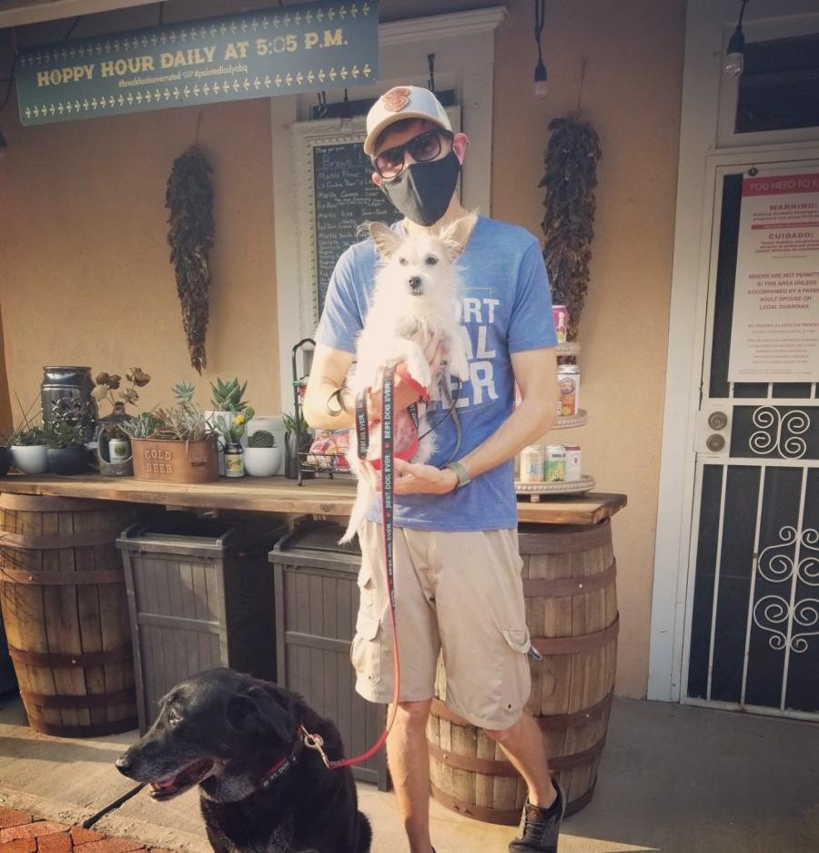 a man standing and posing with two dogs at painted lady bed and brews